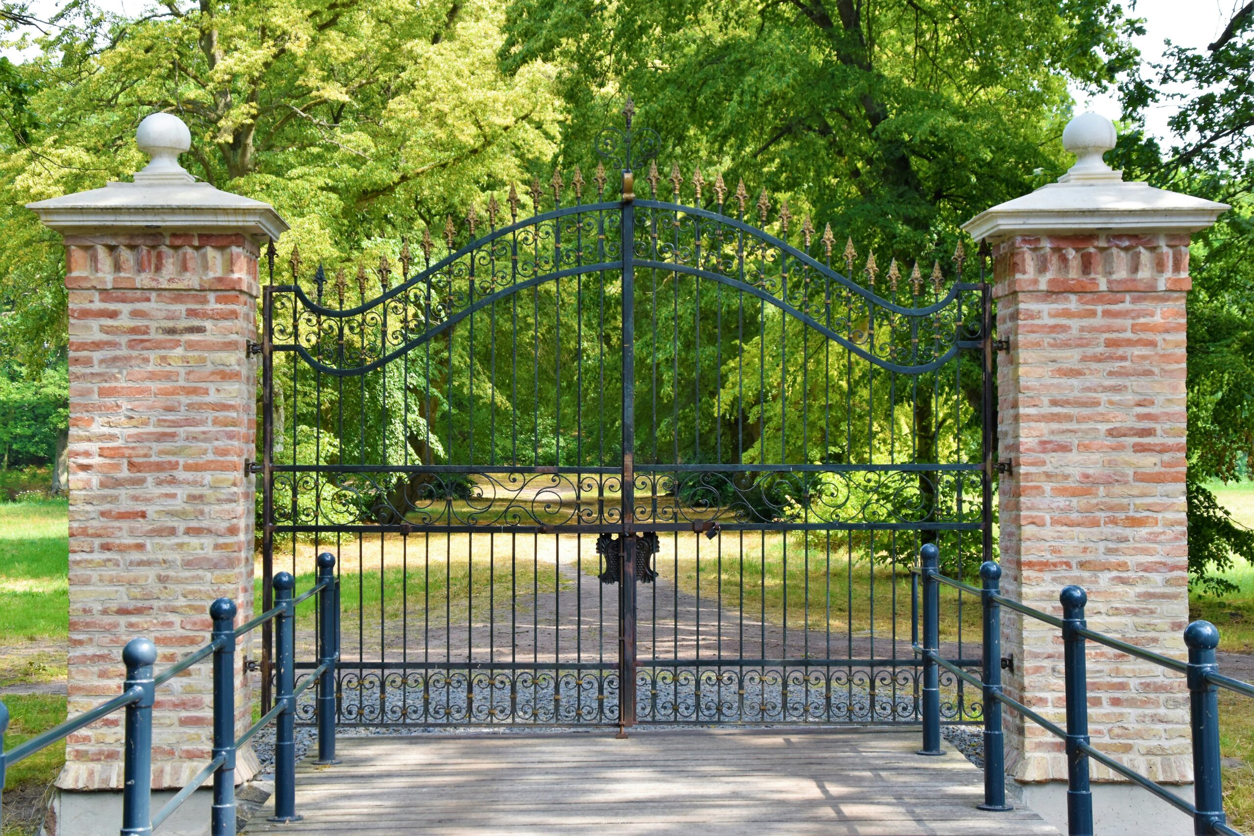 A closed gate into a green area