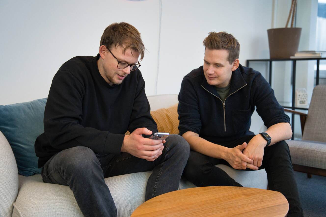 Emil og Oliver sidder i soda og kigger på en telefon